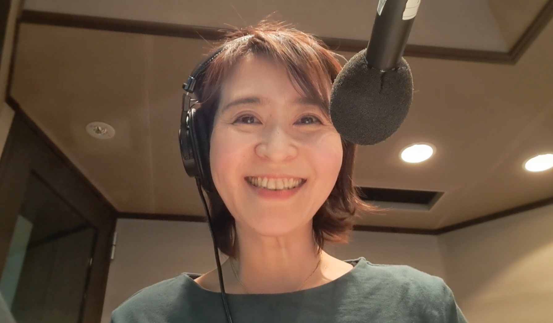 Photo of Natsuko, a professional voice actor, speaking into a studio microphone.